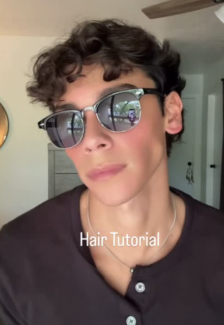 A young man wearing round mirrored shades indoors
